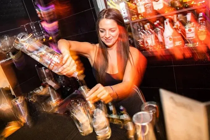 A bartender pouring drinks at the bar